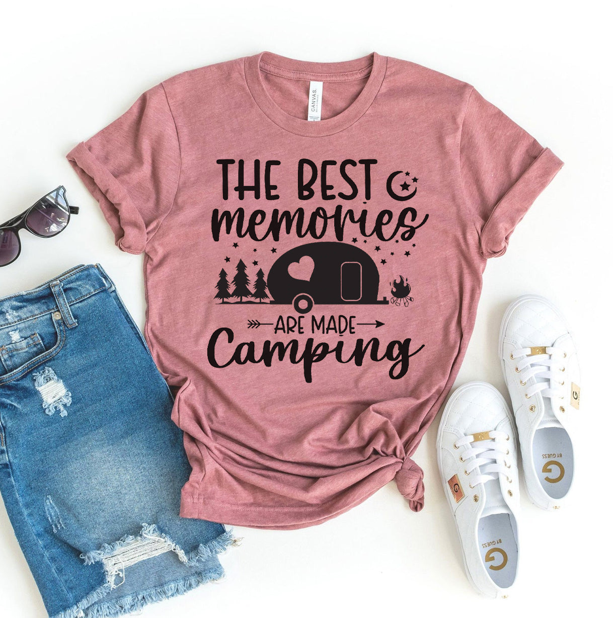 Pink t-shirt with 'The best memories are made camping' text and graphics, paired with denim shorts and white sneakers on a white background.